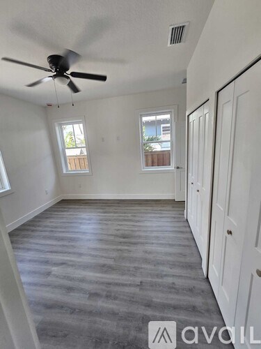 A room with a ceiling fan and two windows.