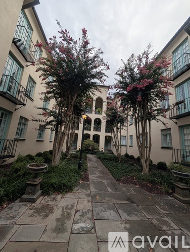 A courtyard with a fountain and a tree with pink flowers.