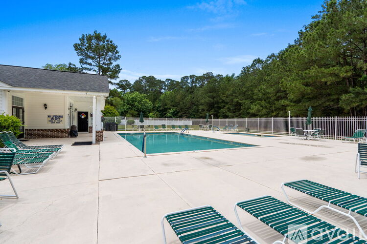 A pool area with sun loungers and a building in the background.