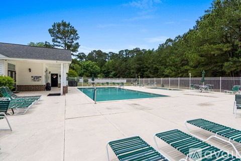 A pool area with sun loungers and a building in the background.