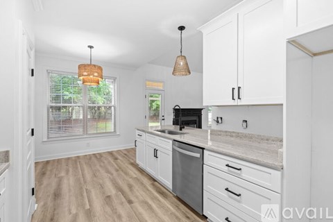 A kitchen with white cabinets and a wooden floor.