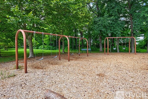 A playground with swings and a seesaw in a park.