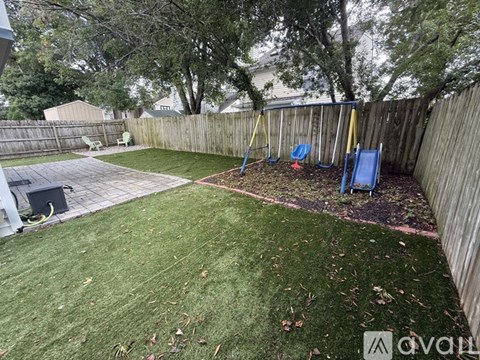 A backyard with a blue slide and a wooden fence.