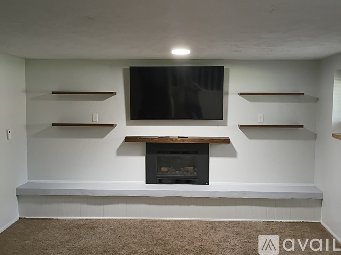 A living room with a fireplace and a flat screen TV mounted on the wall.