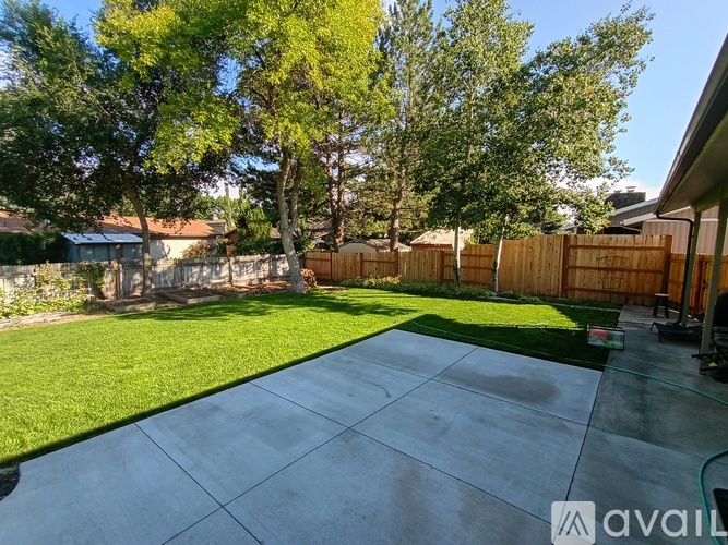 A backyard with a concrete patio and a wooden fence.