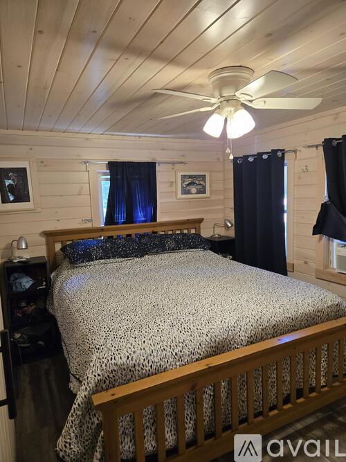 A bedroom with a bed, a ceiling fan, and a window with curtains.