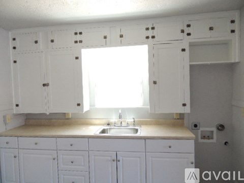 A kitchen with white cabinets and a sink under a window.