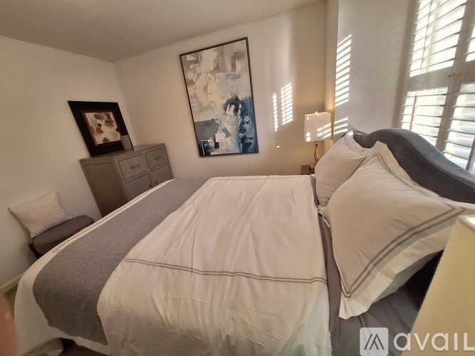 A bedroom with a large bed and a painting on the wall.