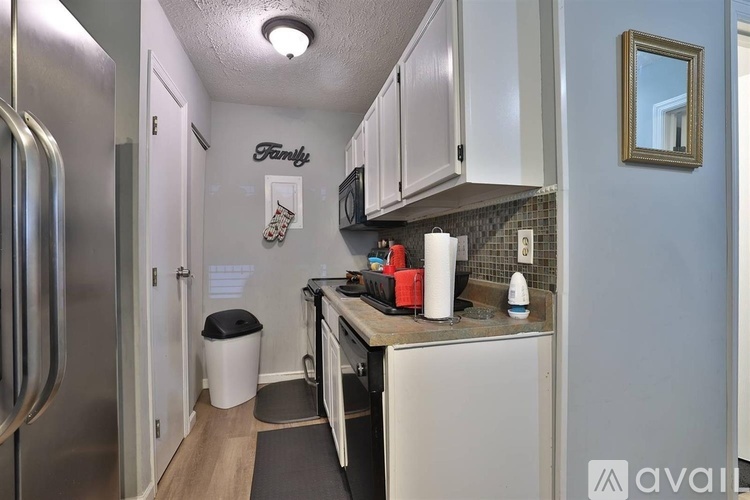 A kitchen with a stainless steel refrigerator and white cabinets.