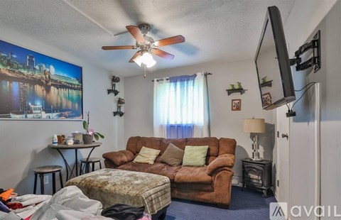 A living room with a brown couch and a ceiling fan.