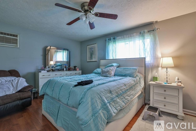 A bedroom with a bed, dresser, and ceiling fan.