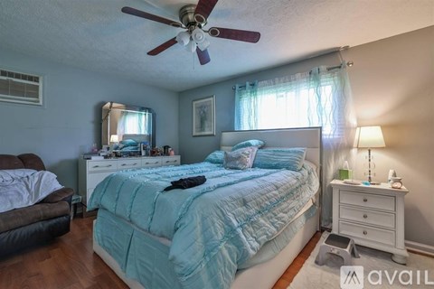 A bedroom with a bed, dresser, and ceiling fan.