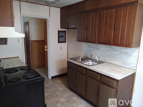 A kitchen with a black stove top oven and wooden cabinets.