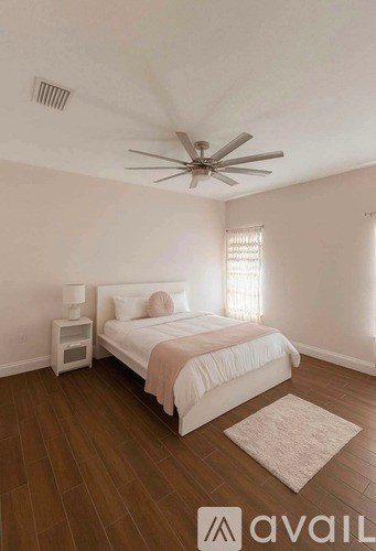 A bedroom with a bed, nightstand, and a ceiling fan.