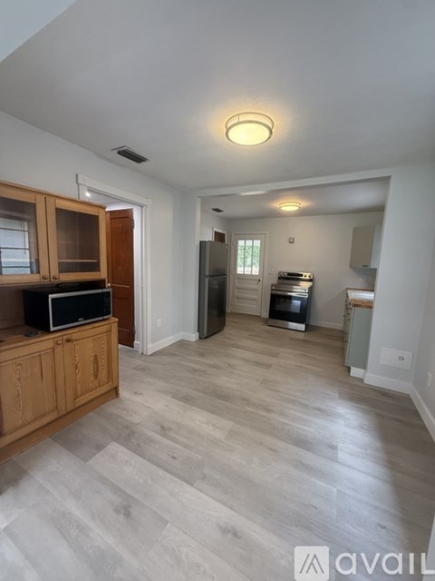 A living room with a television and a kitchen area in the background.
