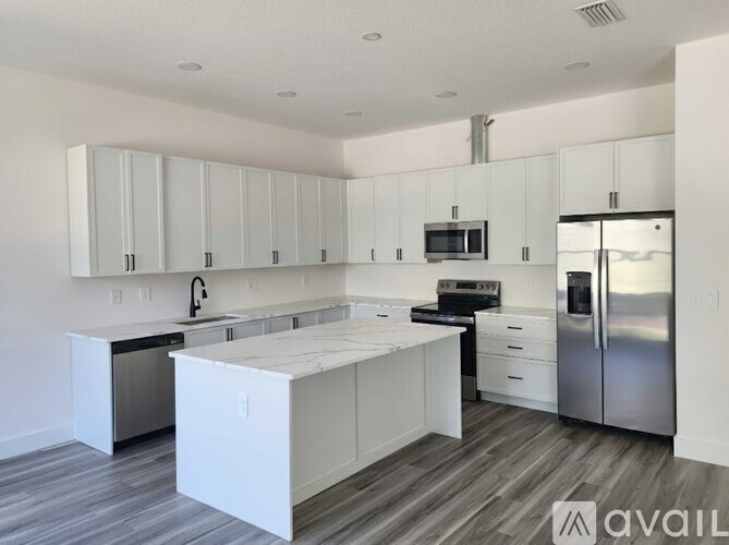 A kitchen with white cabinets and a wooden floor.