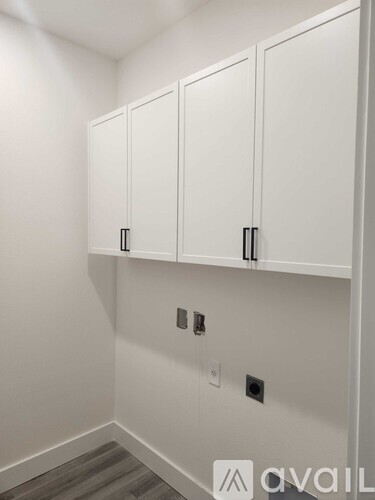 A wall of white cupboards with black handles.