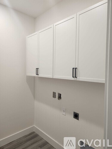 A wall of white cupboards with black handles.