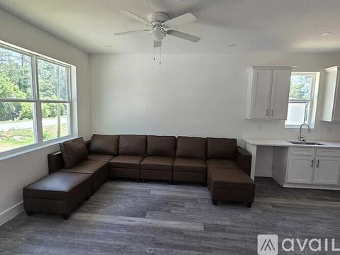 A living room with a brown sectional sofa and a ceiling fan.