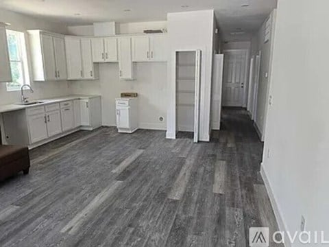 A spacious kitchen with white cabinets and a grey floor.