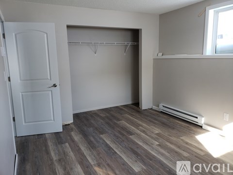 A room with a white door and a grey wall with a wooden floor.