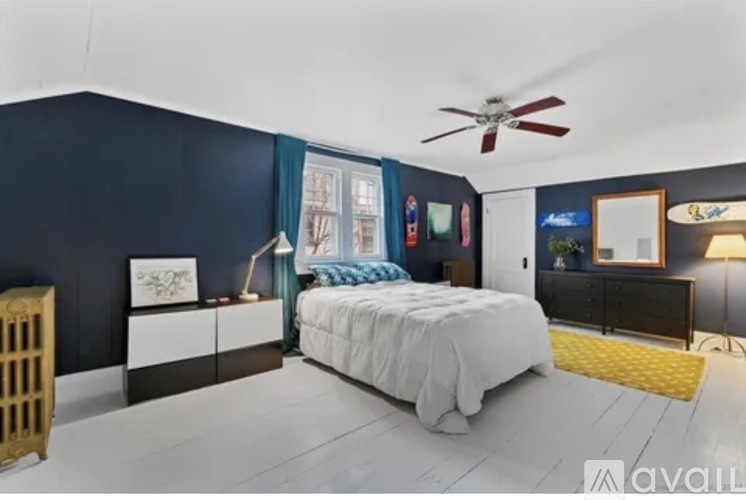 A bedroom with a bed, dresser, and a ceiling fan.