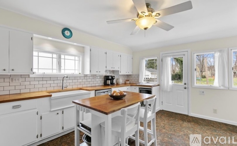 A kitchen with white cabinets and a wooden table.