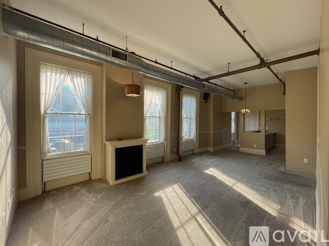 A spacious room with a fireplace and large windows.