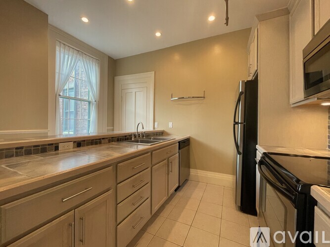 A kitchen with a black refrigerator and white cabinets.