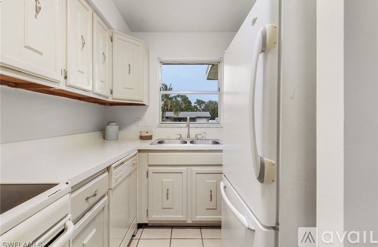 A kitchen with white appliances and cabinets.