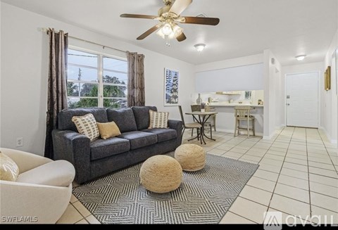 A living room with a grey couch and a ceiling fan.