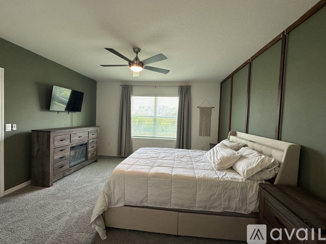 A bedroom with a large bed, a television, and a ceiling fan.