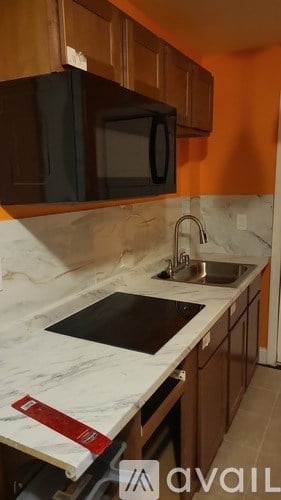 A kitchen with a white countertop and a black microwave above it.