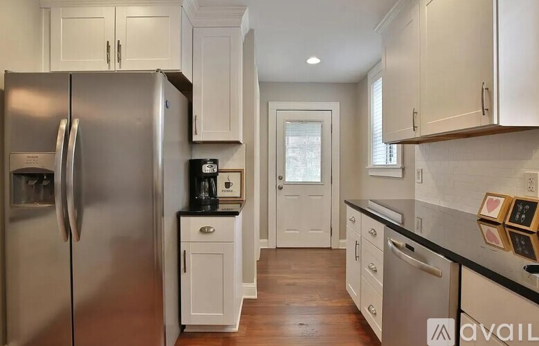 A kitchen with a stainless steel refrigerator and wooden floors.