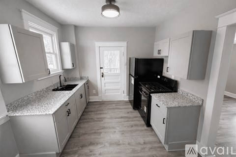 A kitchen with white cabinets and a black stove top oven.