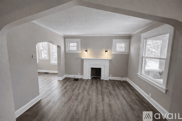 A spacious room with a fireplace and wood flooring.