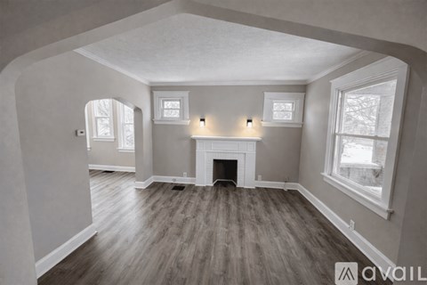 A spacious room with a fireplace and wood flooring.