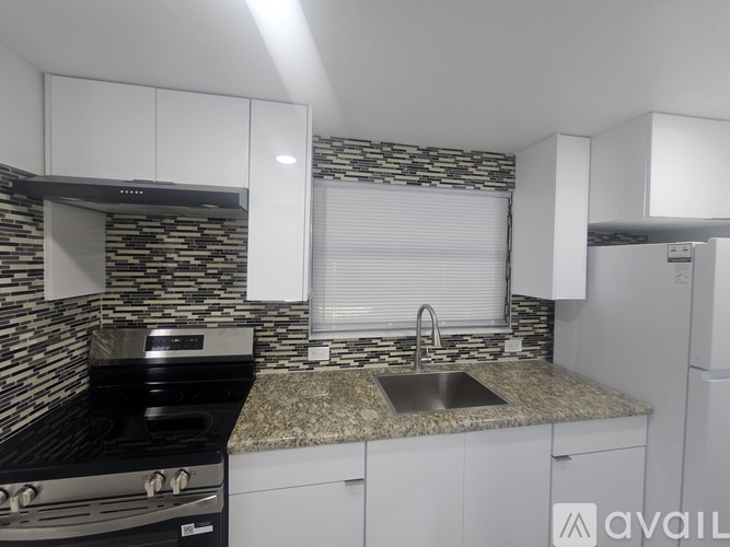 A modern kitchen with a black stove and white cabinets.