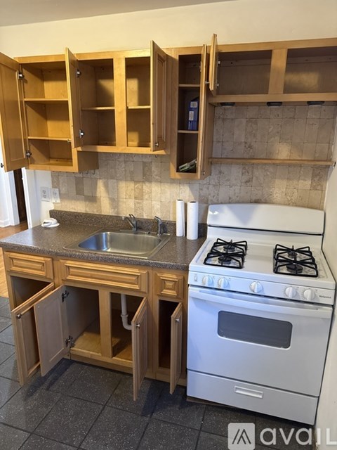 A kitchen with a white stove and wooden cabinets.