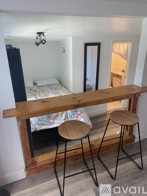A bedroom with a bed, a mirror, and a wooden table with two stools.