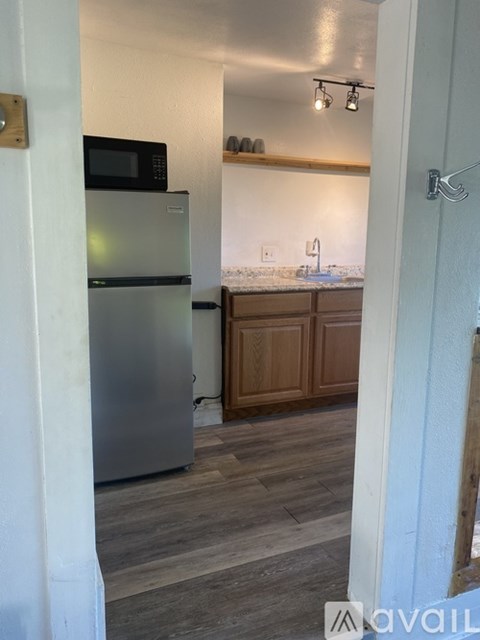 A kitchen with a refrigerator, microwave, and wooden cabinets.