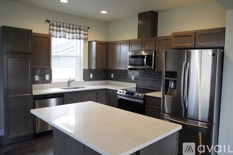 A kitchen with a white counter top and stainless steel appliances.