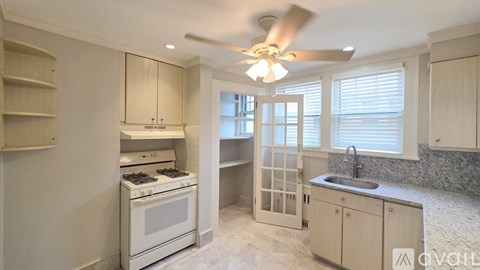 A kitchen with a white stove top oven and a white fan.