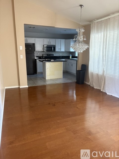 A kitchen with wooden floors and a chandelier.