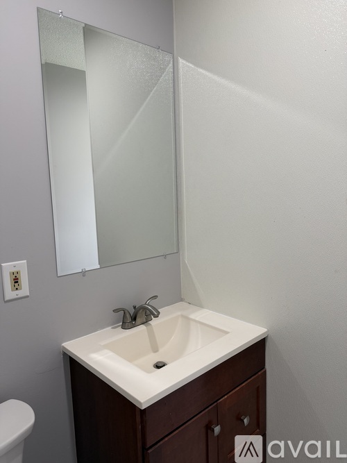 A white sink with a brown cabinet and a mirror above it.