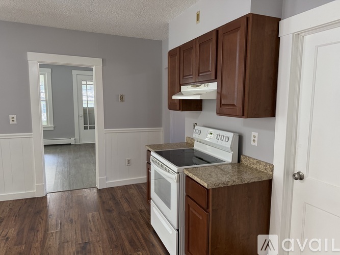 A kitchen with brown cabinets and a white stove top oven.
