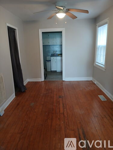 A room with a ceiling fan and wooden floors.