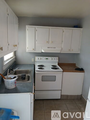 A kitchen with white cabinets and a stove top oven.