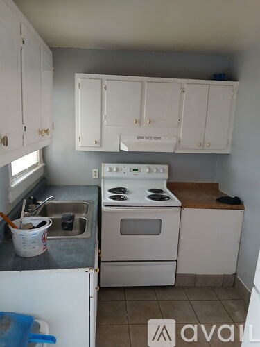 A kitchen with white cabinets and a stove top oven.
