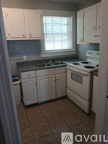 A kitchen with white cabinets and a stove top oven.